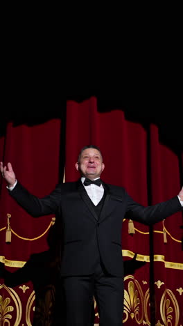theatrical stage. man in costume appearing on a scene and presents the performance in light spot on dark background. vertical video