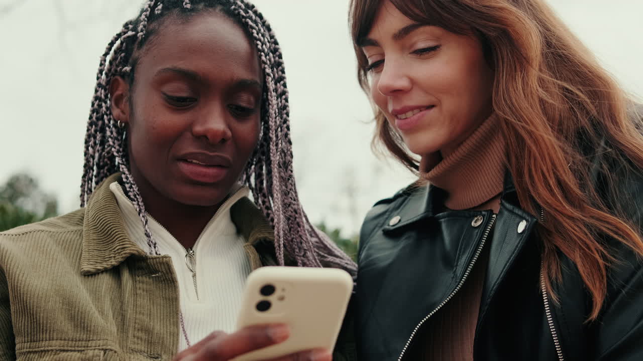 Two young women looking at a phone outdoors