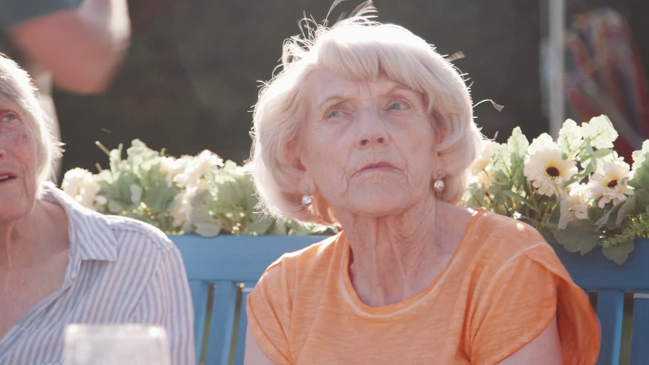 여름 정원 축제 에서 벤치 에 앉아 있는 고위 여성 친구 들 의 그룹 의 느린 움직임  ⁇