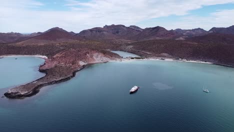 Aerial-wide-view-of-the-beautiful-Playa-Pichilingue-near-Pichilingue-port-of-La-paz-in-Baja-California-Sur-Mexico-with-blue-sea-with-floating-ships-and-rocky-landscape