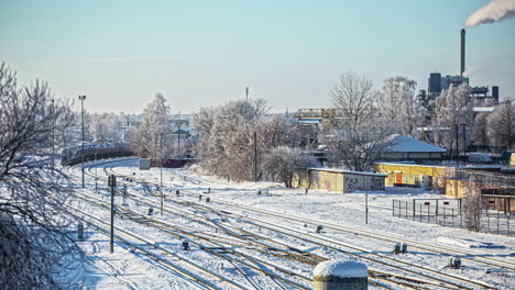 Ein-Kesselzug-Fährt-An-Einer-Fabrik-Vorbei,-Während-Im-Winter-Dampf-Aus-Dem-Schornstein-Austritt---Zeitraffer