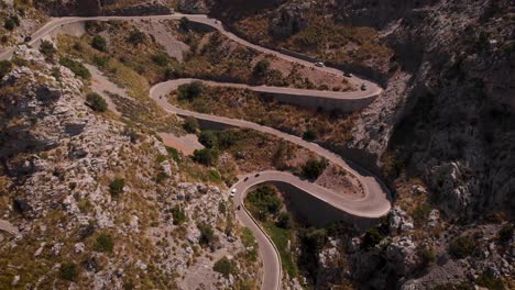 aerial: cars and motorbikes on curvy serpentine road in the mountains