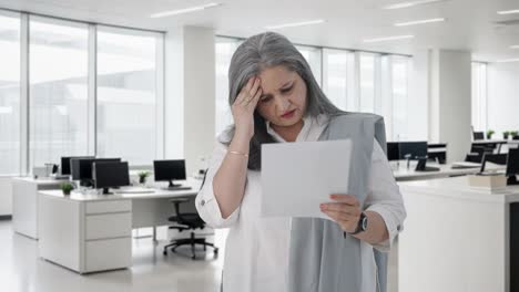 confused indian senior female manager reading business reports