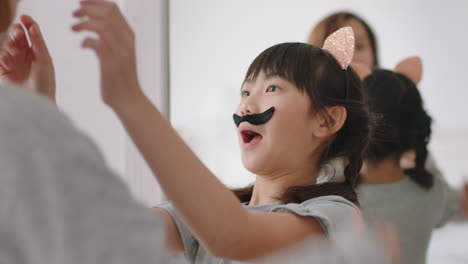 asian mother and daughter playing dress up game at home wearing cat ears little girl having fun with mom enjoying playful day with child together on weekend happy family 4k footage