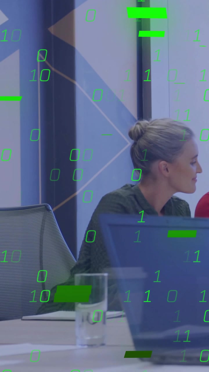 Vertical video: Woman turning at table while data feed filling green overlay hiding laptop for tech