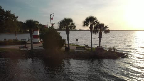 Slow-pan-of-Aerial-drone-wide-shot-of-marina-boat-dock-with-lighthouse-at-the-bay-palm-trees