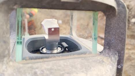 a construction laser spinning while worker sets up receiver in the back ground