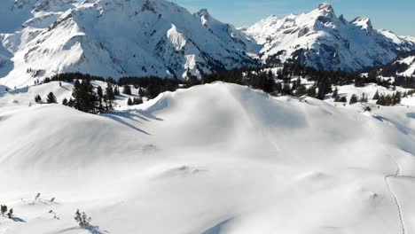 spectacular view flying over the mountain ranges and spotting a hiker atop a smaller peak in warth, a small municipality in vorarlberg, austria on a clear and sunny day in 4k