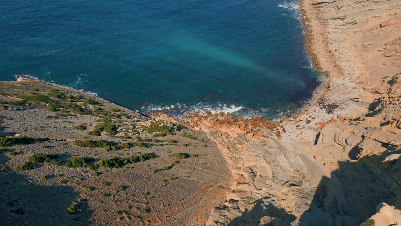 Drone turquoise sea water washing stone shore in super slow motion. Cozy bay