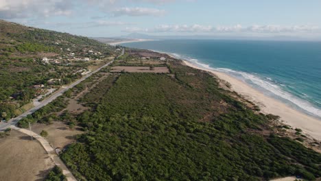 Aerial-view-of-Tarifa,-Spain-with-the-local-road-running-parallel-to-the-ocean-on-a-nice-sunny-day