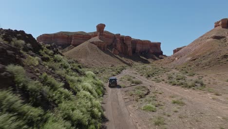 Un-Vehículo-Que-Viaja-A-Través-Del-Desierto-Cerca-Del-Parque-Nacional-Charyn-Canyon-En-Kazajstán,-Asia-Central---Retroceso-Aéreo