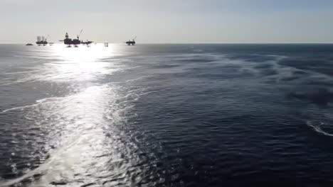 captivating aerial views of offshore oil platforms surrounded by reflective ocean waters during sunset, showcasing industrial beauty and natural serenity
