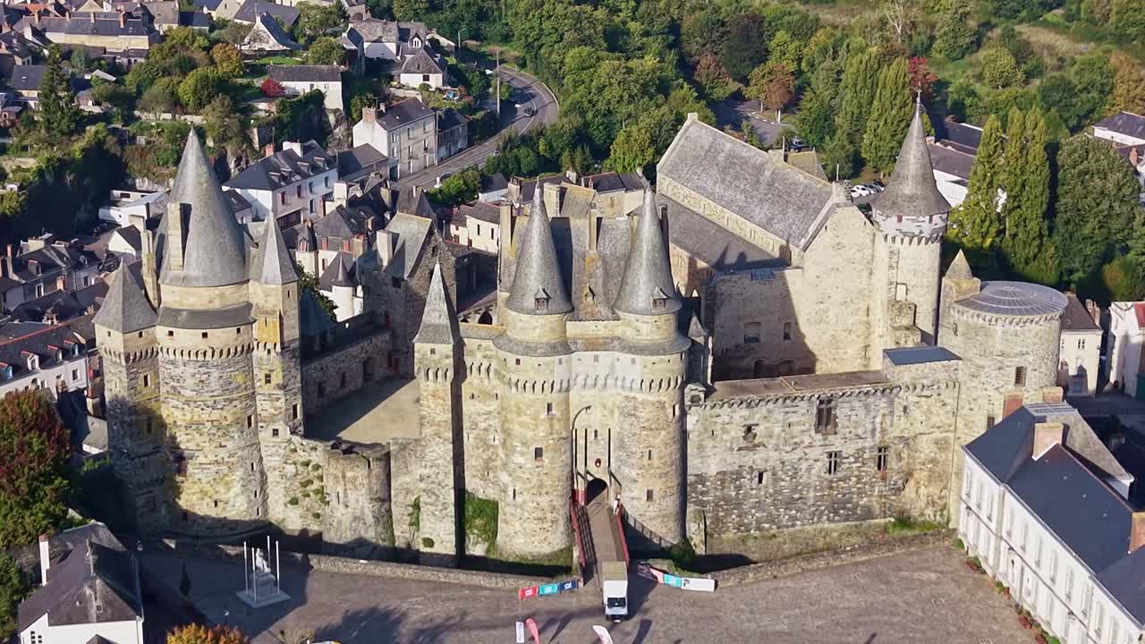 Medieval Vitre Castle in Brittany, France surrounded by town and stone walls in sunny weather, aerial pullback ascend