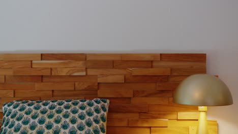 Slow-descending-shot-of-a-bedroom-with-a-wooden-headboard-and-bedside-lamp