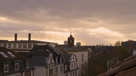 sunset view over rooftops and clock tower in frankfurt am main, cloudy weather