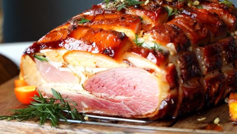 a ham on a cutting board with a sprig of rosemary on top