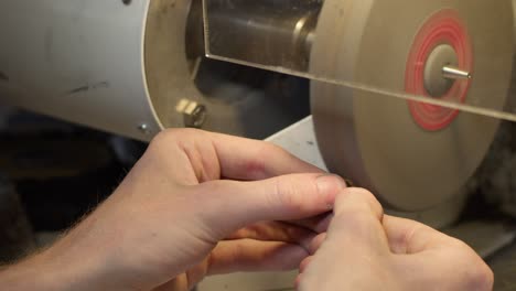 gold wedding ring with diamond getting polished on machine by jeweler