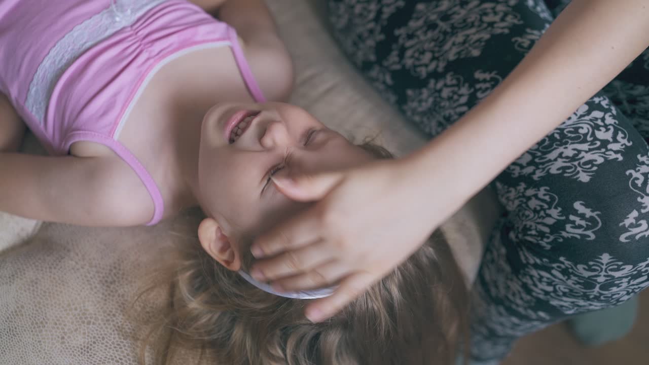 mamá le da gotas para los ojos a la niña acostada en una cama suave