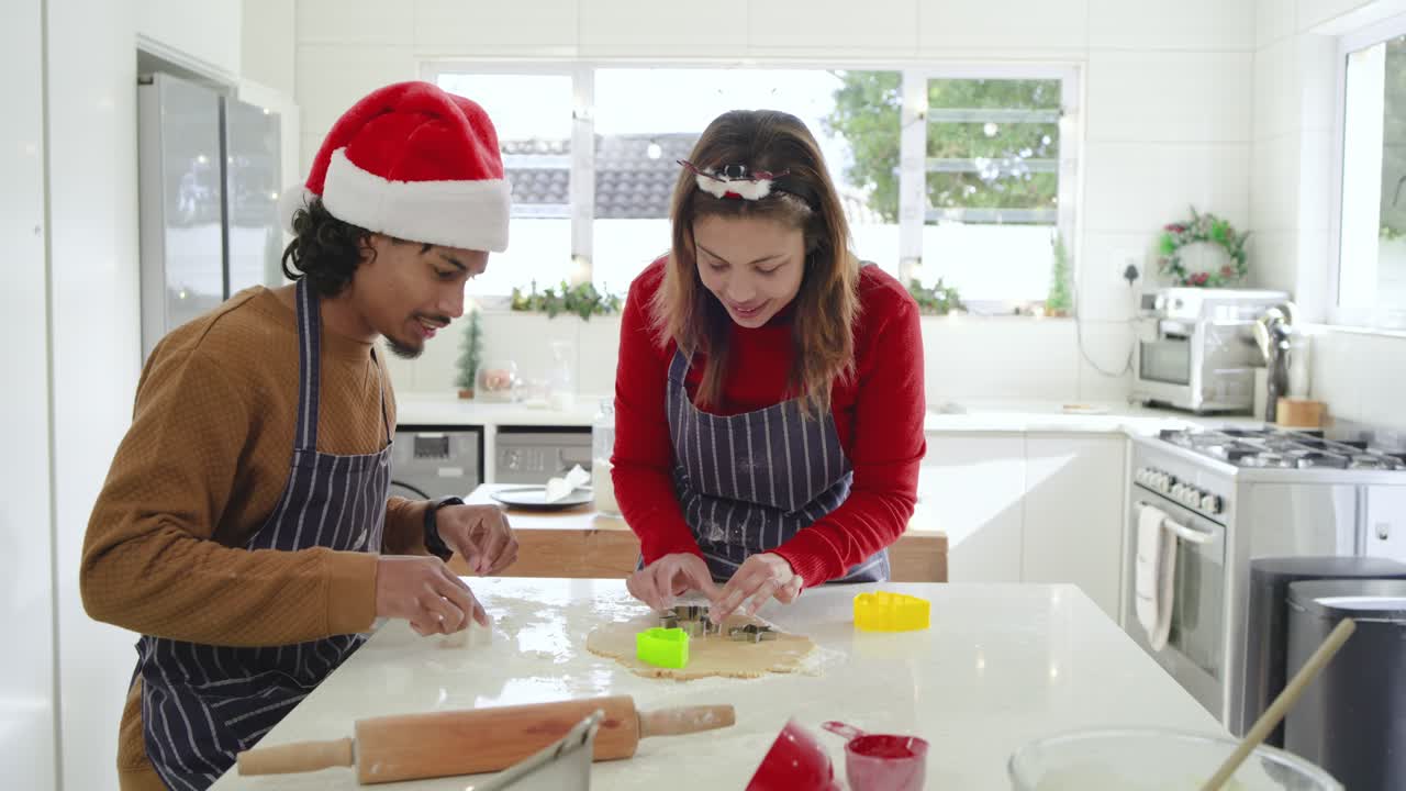 Couple adjusting headgear cutting shapes with cookie cutters on kitchen island for holiday baking