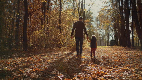 father and children walking in the park and enjoying the beautiful autumn nature. happy family on autumn walk. slow motion. high quality 4k footage