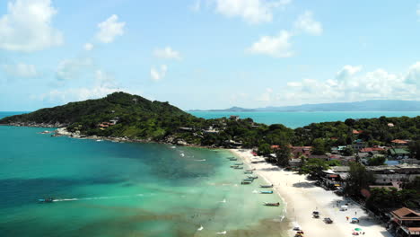 Aerial-view-of-a-beach-in-Thailand,-with-boats-and-people-walking