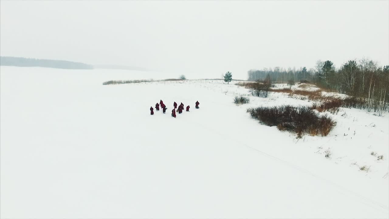 Monges Caminhando sobre Lago Congelado no Inverno