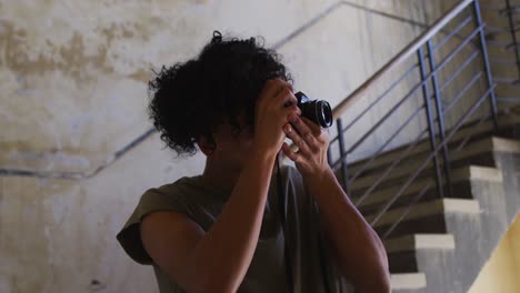 african american man taking pictures with digital camera while standing near stairs