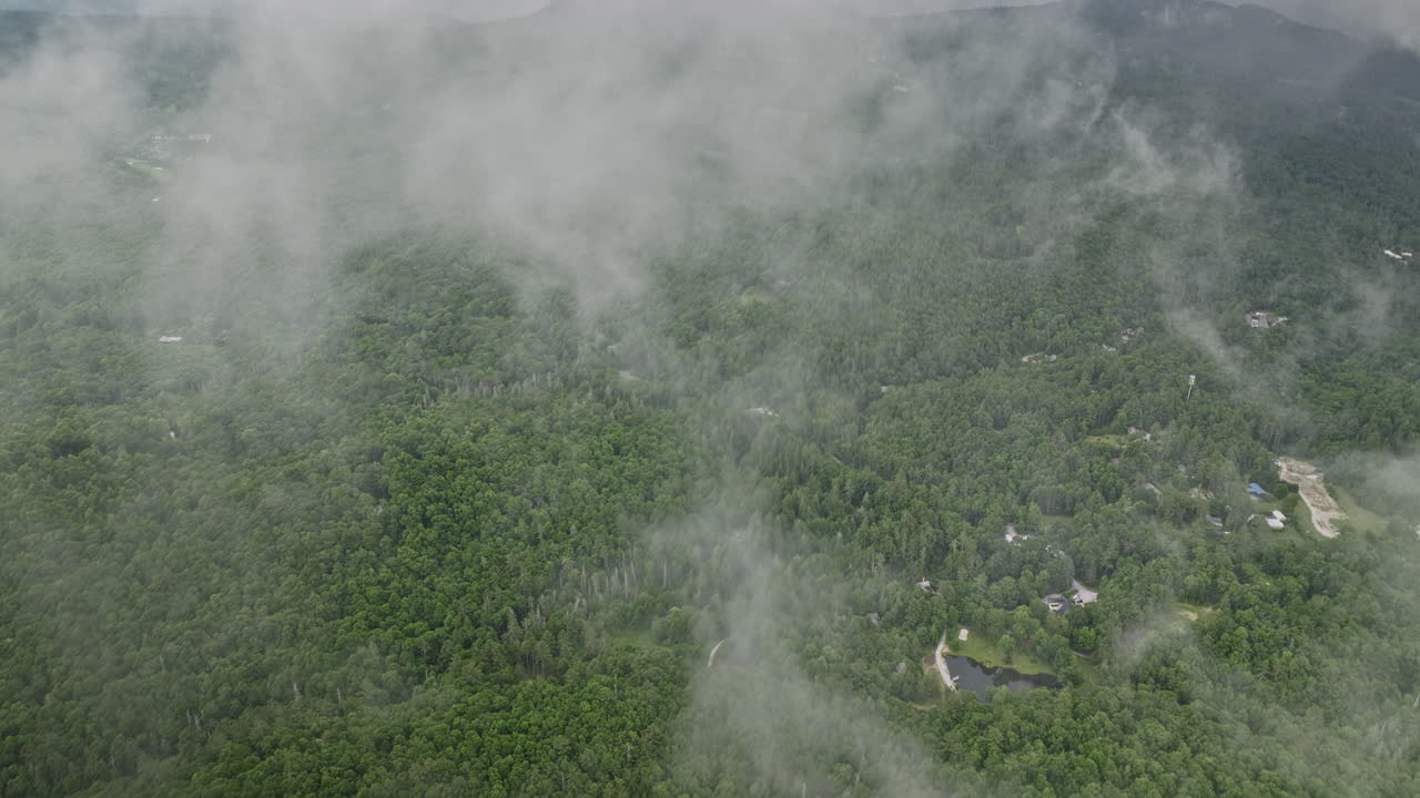 tierras altas carolina del norte aéreo v20 avión no tripulado sobrevuela granja de montaña plana a través de una pieza de nubes escasas, inclinar hacia abajo vista de pájaros capturando densos bosques verdes exuberantes - filmado con mavic 3 cine - julio 2022