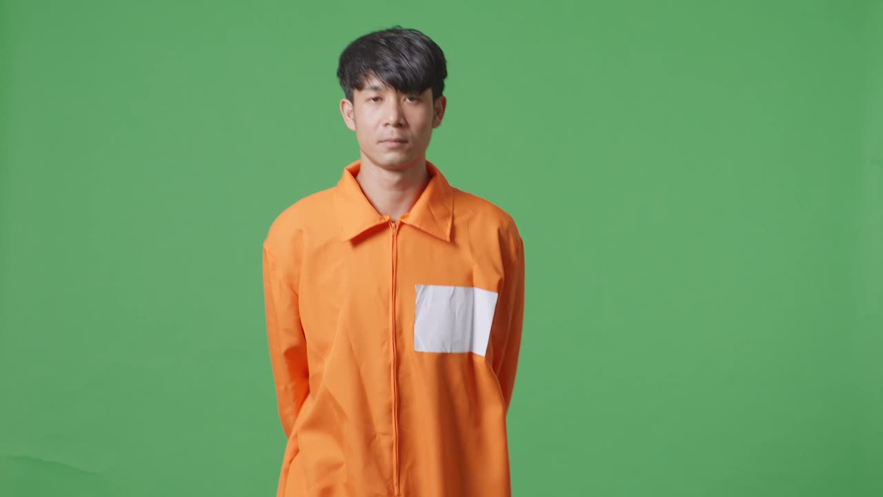 손을 은 아시아 남성 수감자가 녹색 화면 배경에서 고 있습니다.