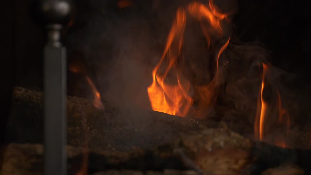Closeup bright warm glowing smoking flames from log burning fire slow motion