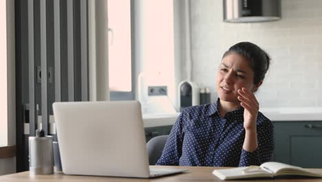 una mujer india que trabaja en una computadora portátil se siente irritada debido a problemas con el dispositivo.