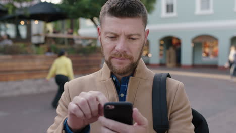 Retrato-De-Un-Encantador-Hombre-Caucásico-Enviando-Mensajes-De-Texto-Usando-Una-Aplicación-De-Redes-Sociales-Para-Teléfonos-Inteligentes-En-El-Fondo-Urbano