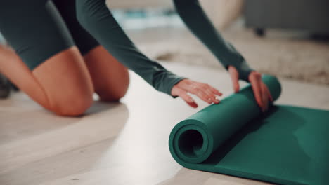 woman rolling up a green yoga mat