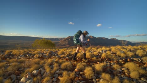 hiker walks along ridge with mountains in background, central australia