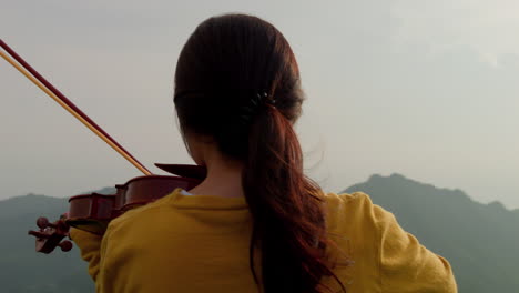 Toma-En-Cámara-Lenta-De-Una-Mujer-Morena,-Desde-Atrás,-Tocando-El-Violín