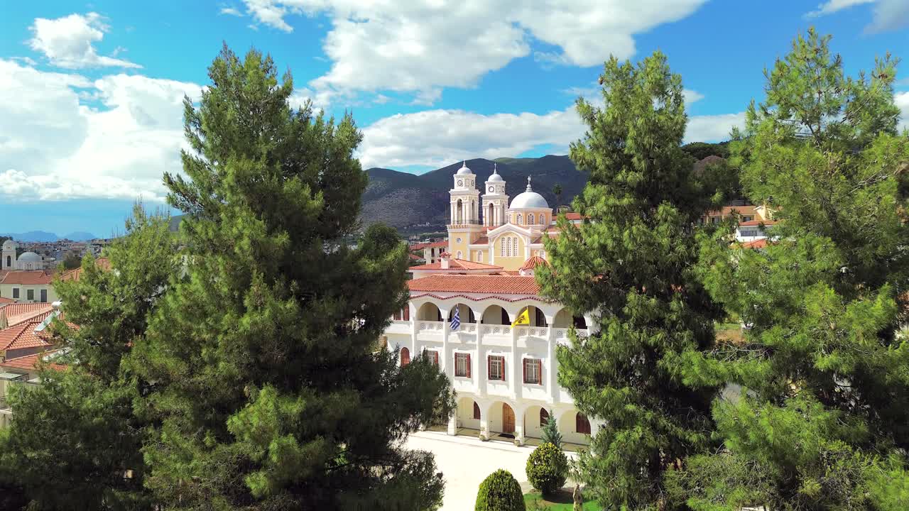 Aerial fast push in , raise up footage, revealing iconic cathedral church Ypapanti at Historical center of Kalamata, between pine trees showcasing beautiful cityscape and ancient castle 4K