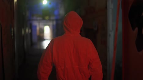 hombre con traje de protección camina por el pasillo oscuro