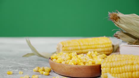 the grain of corn falling on a wooden plate.