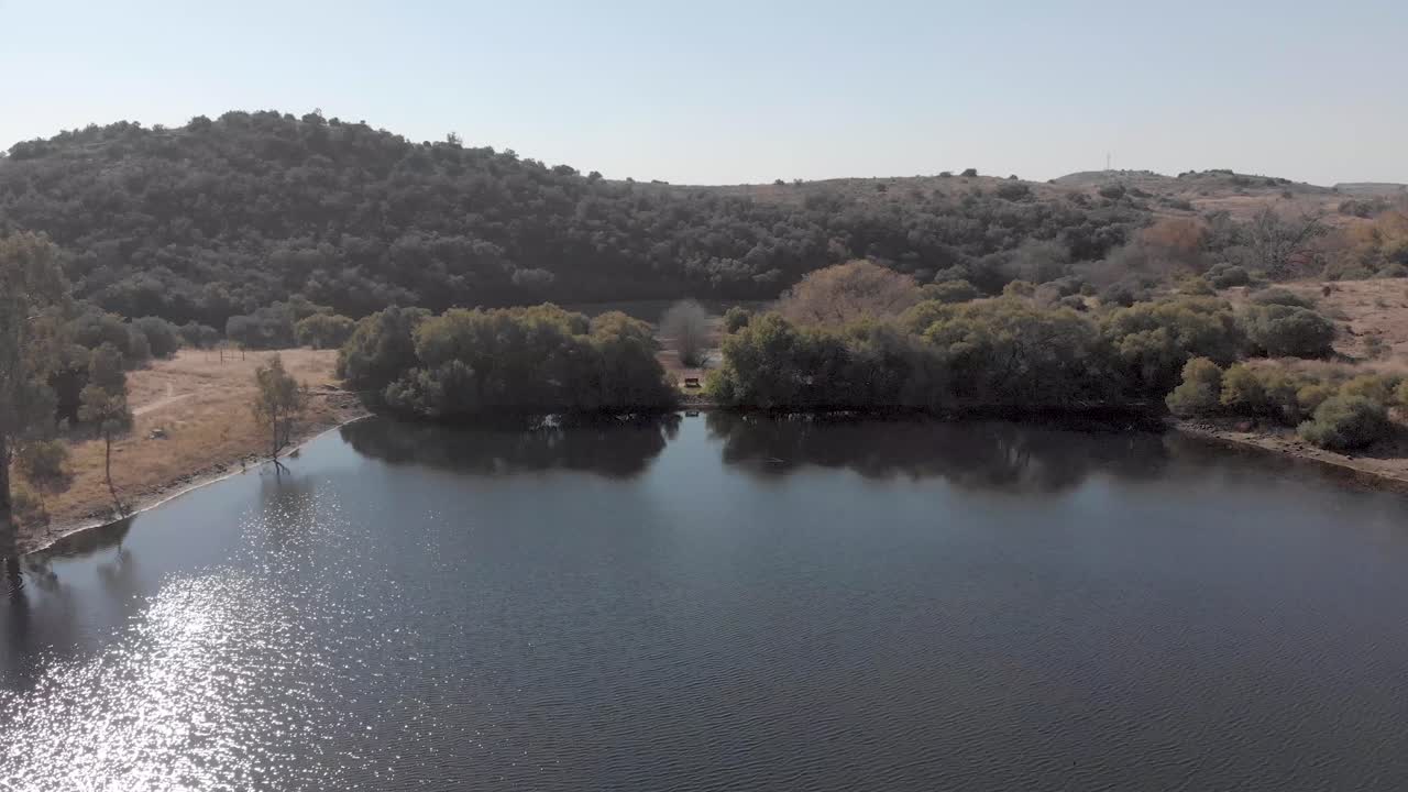 toma aérea inversa sobre un tranquilo lago de hombre sentado en un banco