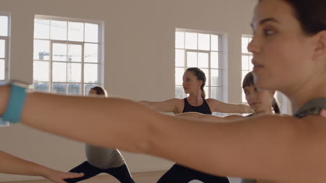 yoga class of healthy pregnant women practicing warrior pose enjoying group physical fitness workout with instructor in studio at sunrise