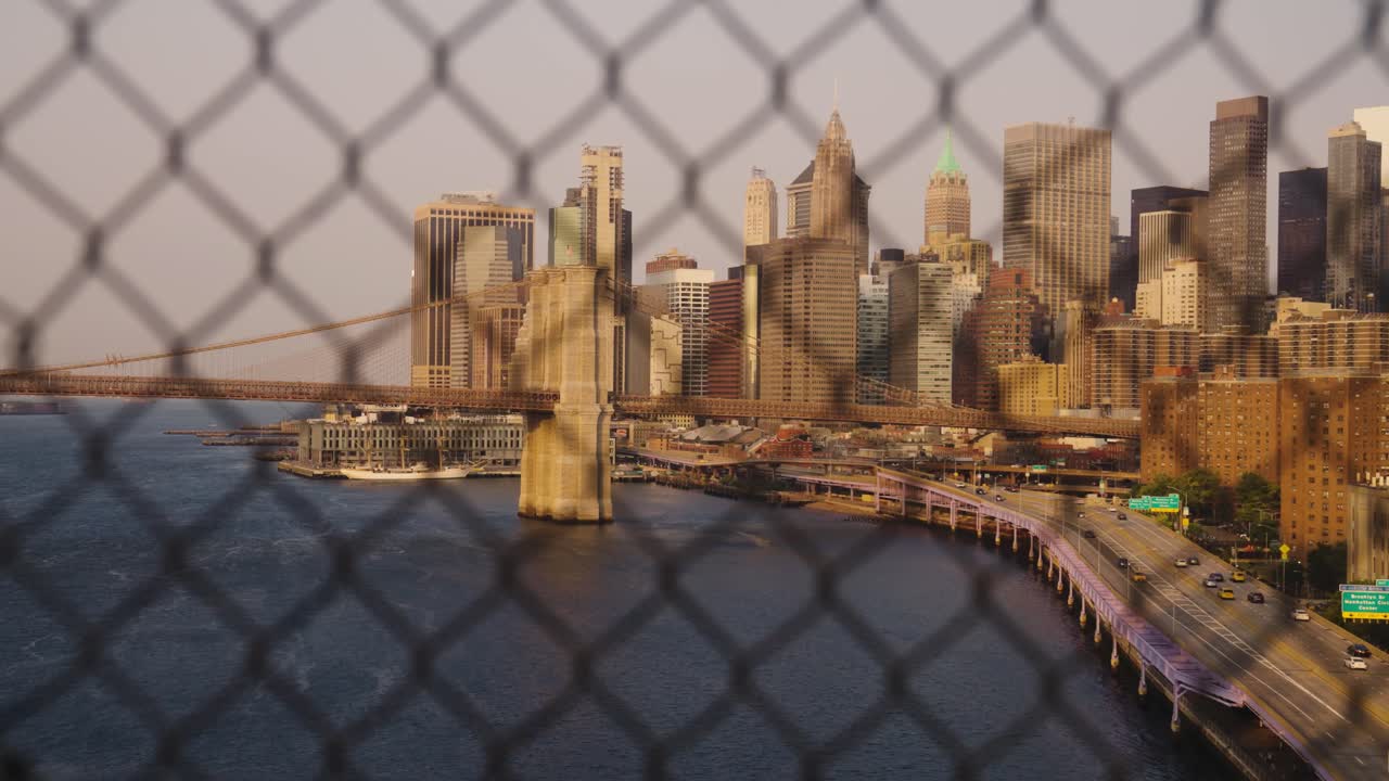Panning shot of showing famous Skyline with Skyscraper of New York behind fence of Manhattan Bridge