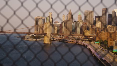 panning shot of showing famous skyline with skyscraper of new york behind fence of manhattan bridge