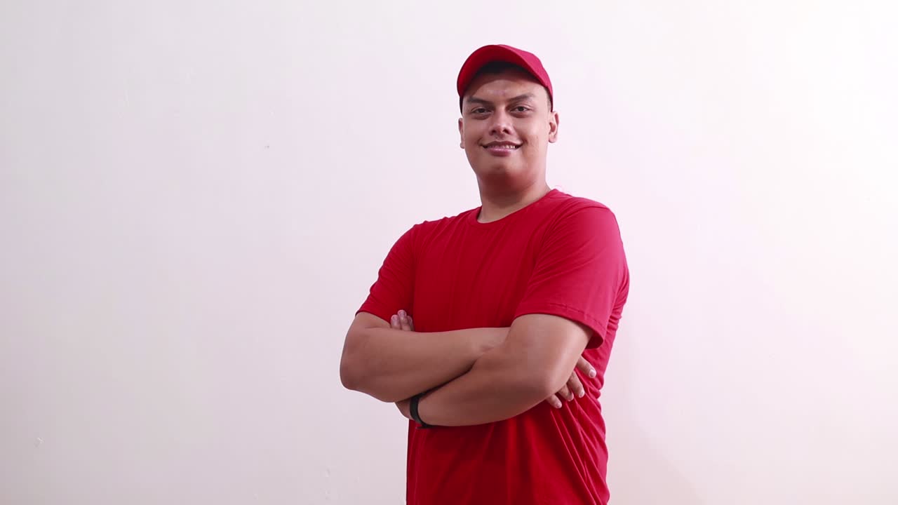 joven mensajero asiático confiado de pie mientras sonríe y mira a la cámara