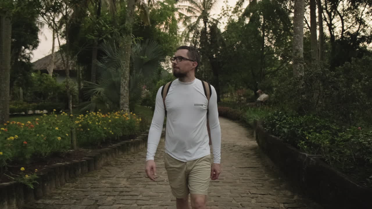 hombre caminando por un jardín tropical