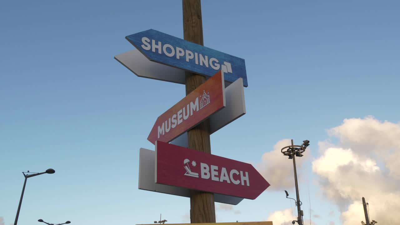 Different signs pointing at beach, shopping and museum at daylight and blue sky