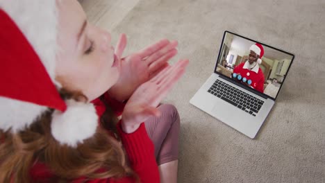 Caucasian-woman-wearing-santa-hat-on-laptop-video-chat-during-christmas-at-home