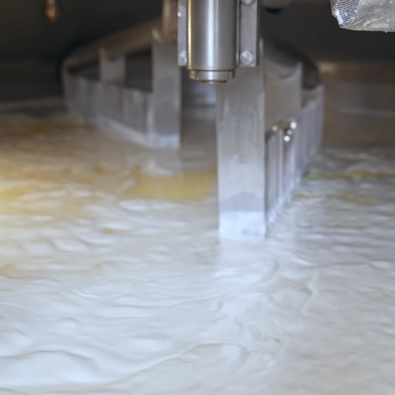 Two big automatic nozzles turning and mixing the dairy product. Fermented milk being mixed up in a big tank. Butter and cheese manufacturing at modern plant