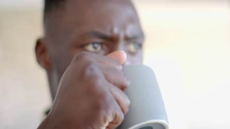 un soldado afroamericano pensativo bebiendo café y mirando hacia adelante en una habitación soleada, en cámara lenta.
