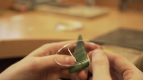 close-up shot of fixing greenstone from new zealand with silver wire - jewelry making - slow motion