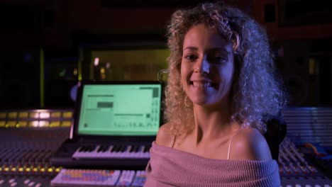 Female-sound-engineer-sitting-at-a-mixing-desk